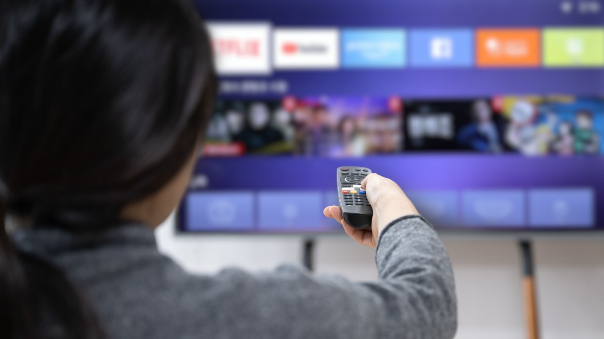 A woman experiences OTT service using a smart TV at home